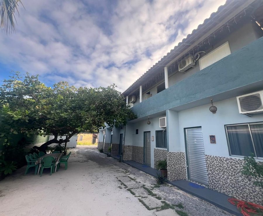 Prédio do Residencial Rio Mar visto do pátio, com árvore e mesas na frente