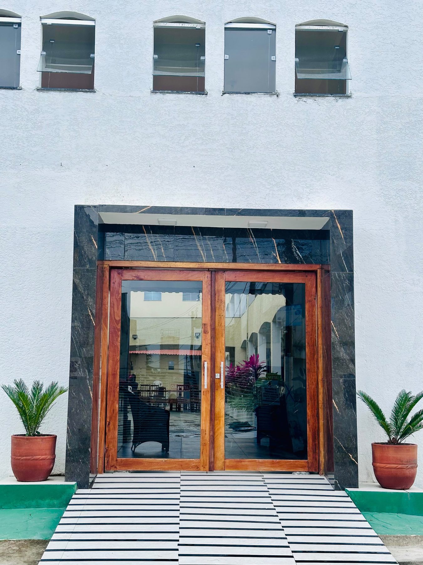 Porta de entrada da pousada, com vasos de planta dos dois lados