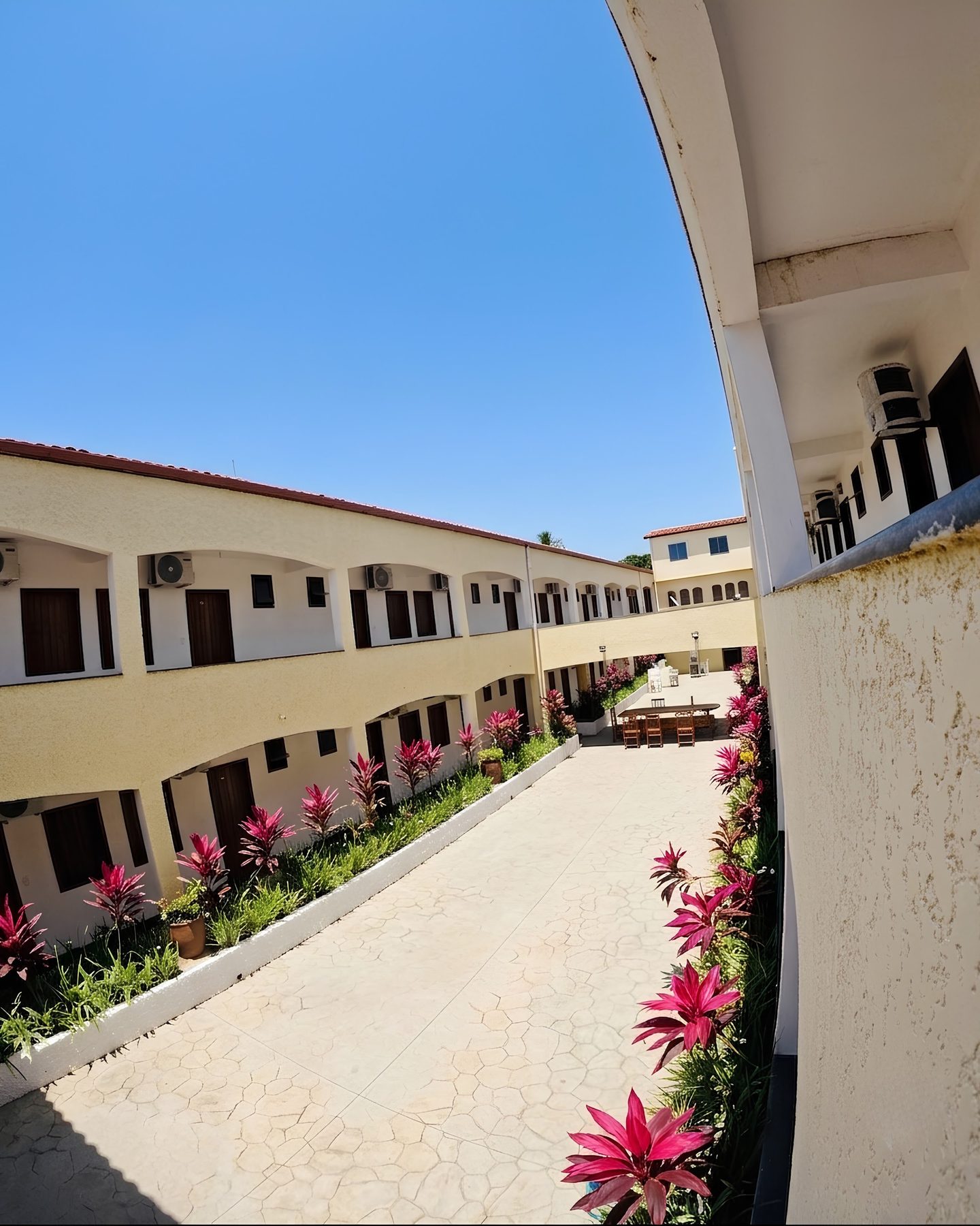 Pátio interno da pousada com floreiras e apartamentos dos dois lados