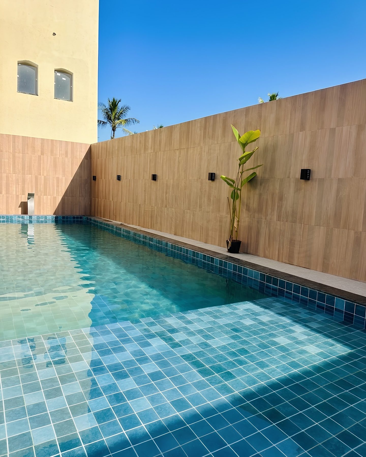 Piscina vista de outro ângulo, com muro de madeira ao fundo