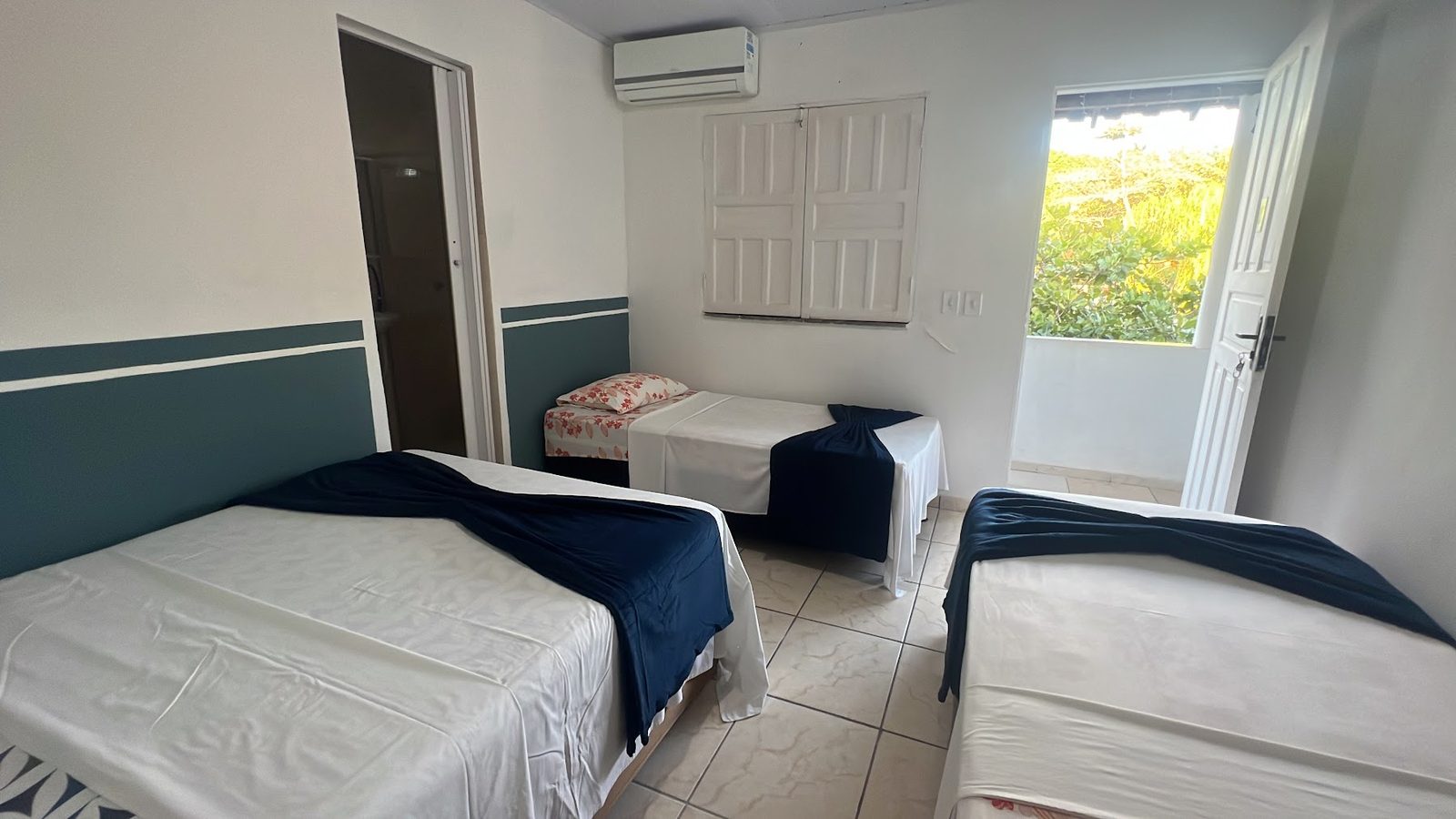 Suíte 7: cama de casal arrumada, ar-condicionado e janela