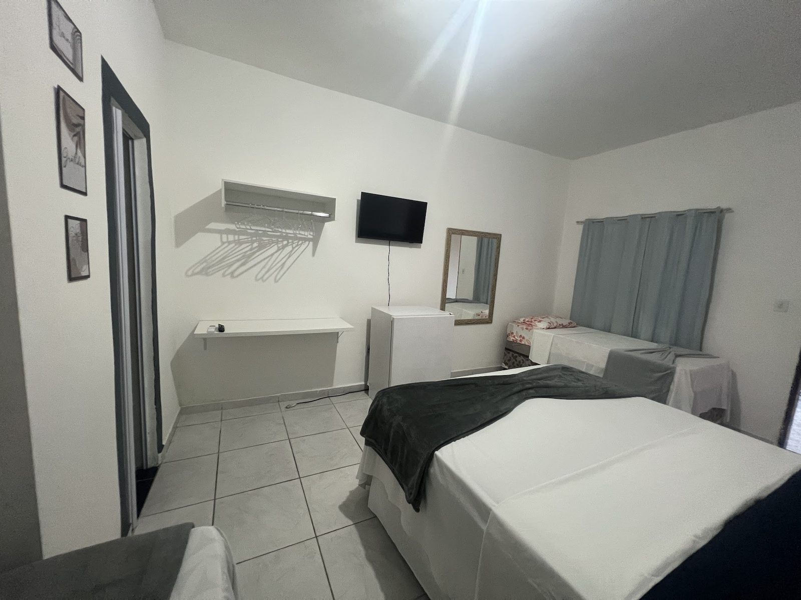 Suíte 11: cama de casal arrumada, TV, quadros e ambiente claro