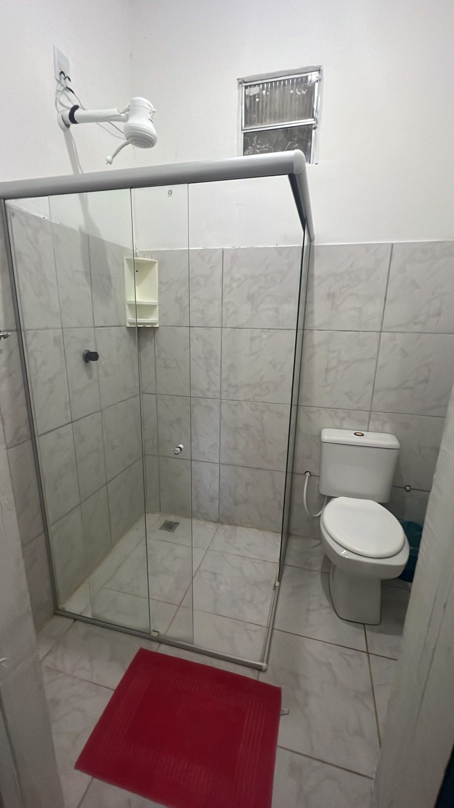 Banheiro da suíte 12, com box de vidro e tapete vermelho