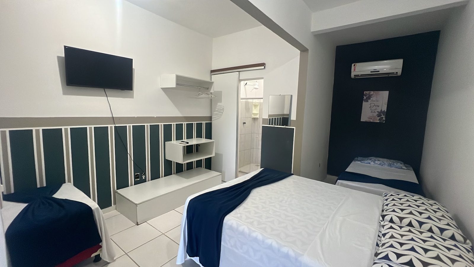 Suíte 12: cama de casal, TV na parede e painel verde